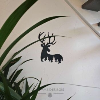 Un cerf de côté avec des sapins.