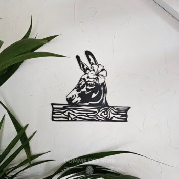 Une ânesse avec un fleur sur une barrière.